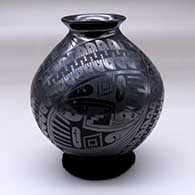A black on glossy black jar with a rolled lip and decorated with a three panel geometric design
 by Eligio Ortiz of Mata Ortiz and Casas Grandes