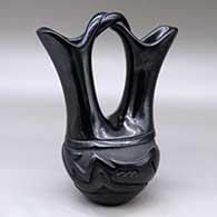 A black wedding vase with a twisted bridge and carved around the body with an avanyu design
 by Reycita Naranjo of Santa Clara