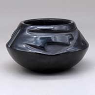 A black bowl with a two panel geometric design carved above the shoulder
 by Juanita Gonzales of San Ildefonso