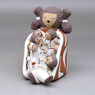 A sitting grandmother storyteller wearing a manta and with four children
 by Chris Teller of Isleta