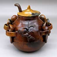 A lidded brown stew pot with six spoons and a ladle
 by Unknown of Dineh