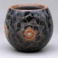 A black jar with a sienna rim and spots decorated with a four panel sgraffito flower and geometric design, plus four inlaid stones
 by Julie Gutierrez of Santa Clara