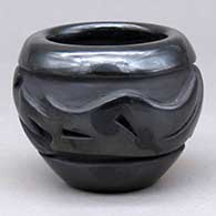 A small black bowl carved around the body with an avanyu and geometric design
 by Jennifer Naranjo of Santa Clara