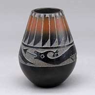 A small black jar with a sienna band around the neck and with a sgraffito avanyu and feather design
 by Corn Moquino of Santa Clara