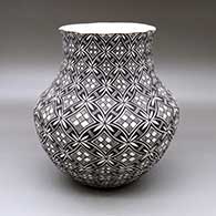 A black on white jar with a pie crust rim and dec orated with a pumpkin seed snowflake, fineline and geometric design
 by Nelda Lucero of Acoma