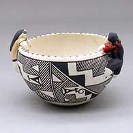 A polychrome bowl decorated with a four panel fineline and geometric design with two children perched on the rim and a third sitting inside
 by Wanda Aragon of Acoma