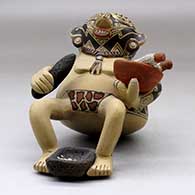 A backward leaning sitting shaman figure holding a knife, a bowl with ears of corn and with a metate between his feet, click or tap to see a larger version