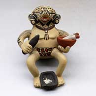 A backward leaning sitting shaman figure holding a knife, a bowl with ears of corn and with a metate between his feet
 by Manuel Rodriguez of Mata Ortiz and Casas Grandes