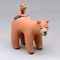 A standing bear with a cub holding a fish on its back
 by Dorothy Herrera of Cochiti