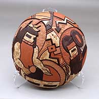 A polychrome mixed clay seed pot decorated on top with a carved, sgraffito and painted masked dancers and geometric design
 by Delmar Polacca of Hopi