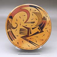 A polychrome plate decorated on top with a bird hanging from sky band, dragonflies and geometric design and a hand with bat wing and geometric design on the back
 by Joshua Namingha of Hopi