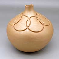 A golden micaceous jar with an organic rim and carved above the shoulder with a geometric design
 by Dominique Toya of Jemez