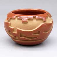 A red bowl polished on the inside and carved on the outside with an avanyu and kiva step geometric design
 by Madeline E Naranjo of Santa Clara