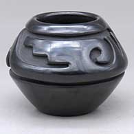 A small black bowl carved with a stylized avanyu design above the shoulder
 by Stella Chavarria of Santa Clara