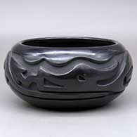 A black bowl carved around the body with an avanyu design
 by Stella Chavarria of Santa Clara