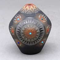 A small black seed pot with a sienna rim and spots, inlaid stones and a sgraffito bear paw and geometric design
 by Ron Suazo of Santa Clara