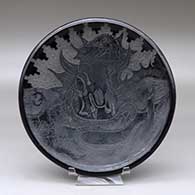 A black plate decorated with a sgraffito serpent, nature scene, kiva step and geometric design
 by Paul Naranjo of Santa Clara