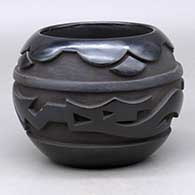 A matte and polished black bowl carved with an avanyu and geometric design around the body
 by Marvin Moquino of Santa Clara