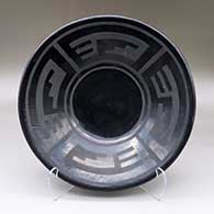 A shallow black on black bowl decorated with a four panel geometric design
 by Margaret Tafoya of Santa Clara