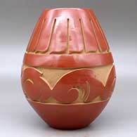 A red jar carved around the body with an avanyu and feather design, click or tap to see a larger version