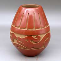 A red jar carved around the body with an avanyu and feather design
 by Kimberly Garcia of Santa Clara
