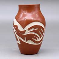 A red vase carved with an avanyu and geometric design around the body, click or tap to see a larger version