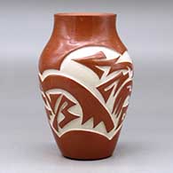 A red vase carved with an avanyu and geometric design around the body, click or tap to see a larger version