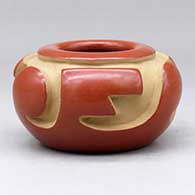 A red bowl decorated around the shoulder with a carved three panel geometric design
 by Anita L Suazo of Santa Clara