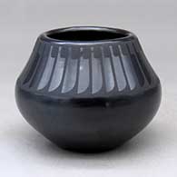 A black on black jar decorated with a ring of feathers design above the shoulder
 by Maria Martinez of San Ildefonso