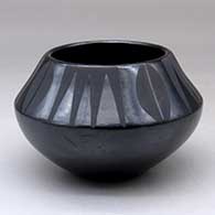 A black on black bowl decorated with a four panel deer print and geometric design above the shoulder
 by Maria Martinez of San Ildefonso