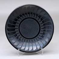 A black on black plate decorated with a ring of feathers and crosshatching design
 by Maria Martinez of San Ildefonso