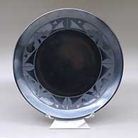 A black on black plate decorated with a ring of geometric design
 by Maria Martinez of San Ildefonso