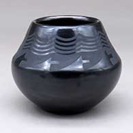 A small black on black jar decorated with a geometric design above the shoulder
 by Maria Martinez of San Ildefonso