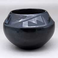 A black on black jar decorated with a four panel geometric design above the shoulder
 by Maria Martinez of San Ildefonso