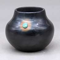 A small black jar decorated with a sienna spot and an inlaid stone
 by Candace Tse Pe of San Ildefonso