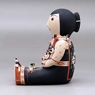 A sitting grandmother storyteller figure with fourteen tiny children, click or tap to see a larger version