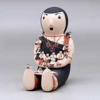 A sitting grandmother storyteller figure with fourteen tiny children, click or tap to see a larger version