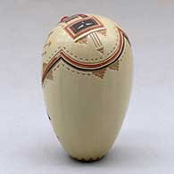 A miniature polychrome seed pot decorated with a lightly carved, sgraffito and painted yeibichai, arrow, rainbow and geometric design, with one inlaid stone, click or tap to see a larger version