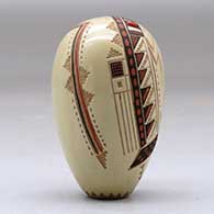 A miniature polychrome seed pot decorated with a lightly carved, sgraffito and painted yeibichai, arrow, rainbow and geometric design, with one inlaid stone, click or tap to see a larger version