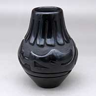 A black jar carved with an avanyu and ring of feathers design
 by Stella Chavarria of Santa Clara