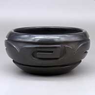 A black bowl with a stylized avanyu design carved around the shoulder
 by Stella Chavarria of Santa Clara