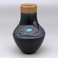 A black and micaceous black vase with a sienna rim, an inlaid turquoise and a lightly carved avanyu design above the shoulder
 by Dora Tse Pe of San Ildefonso