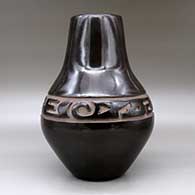 A large black jar carved with a stylized avanyu design around the shoulder, click or tap to see a larger version