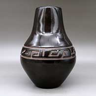 A large black jar carved with a stylized avanyu design around the shoulder, click or tap to see a larger version
