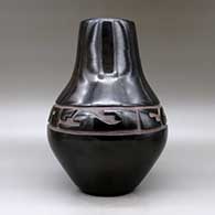 A large black jar carved with a stylized avanyu design around the shoulder, click or tap to see a larger version