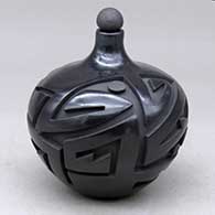 A matte and polished lidded black seed pot carved with a geometric design
 by Autumn Borts of Santa Clara
