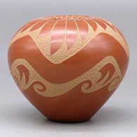 A red seed pot decorated with a sgraffito avanyu, feather and geometric design, click or tap to see a larger version