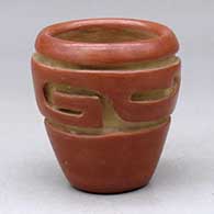 A small red jar carved with a stylized avanyu design
 by Teresita Naranjo of Santa Clara