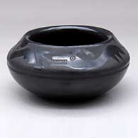 A black on black bowl decorated with an avanyu and cloud design above the shoulder
 by Blue Corn of San Ildefonso