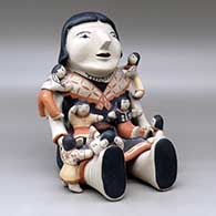 A grandmother storyteller figure with seven children on her
 by Ada Suina of Cochiti